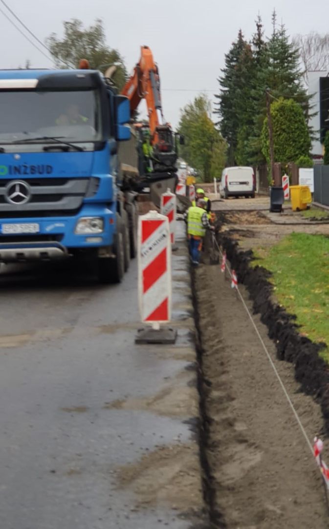 Po lewej stronie niebieski samochód specjalistyczny, po prawej stronie wykopany rów.