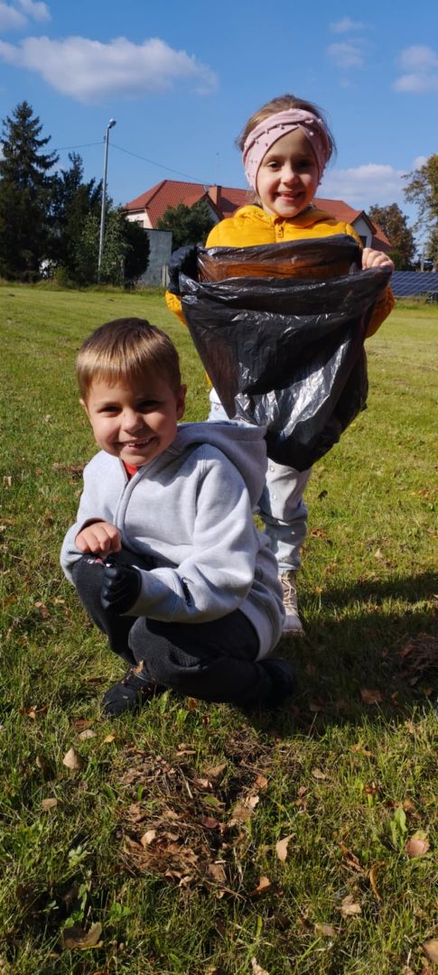 dwoje dzieci jedno trzyma w dłoniach worek na śmieci