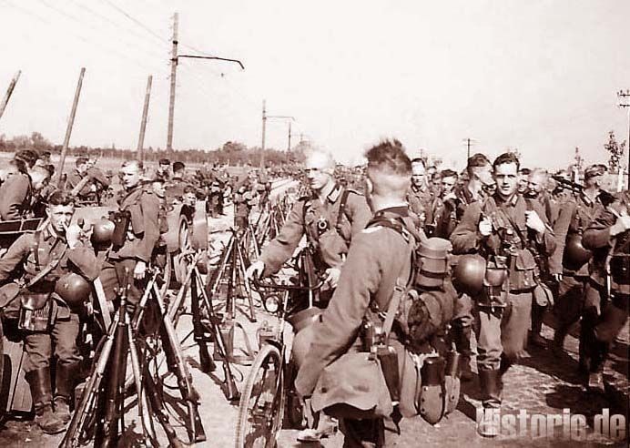 Zdjęcie w sepii przedstawiające grupę żołnierzy stojących na ulicy