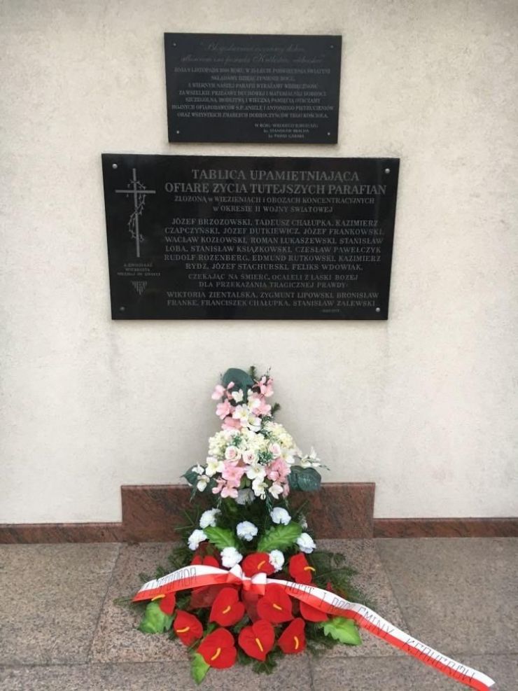 kwiaty pod tablicą pamiątkową przed kościołem 