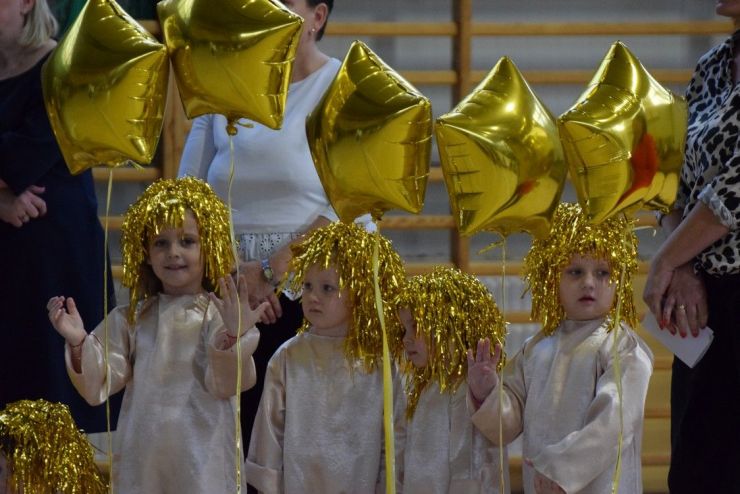 Czworo dzieci przebrane za aniołki trzymające złote balony.