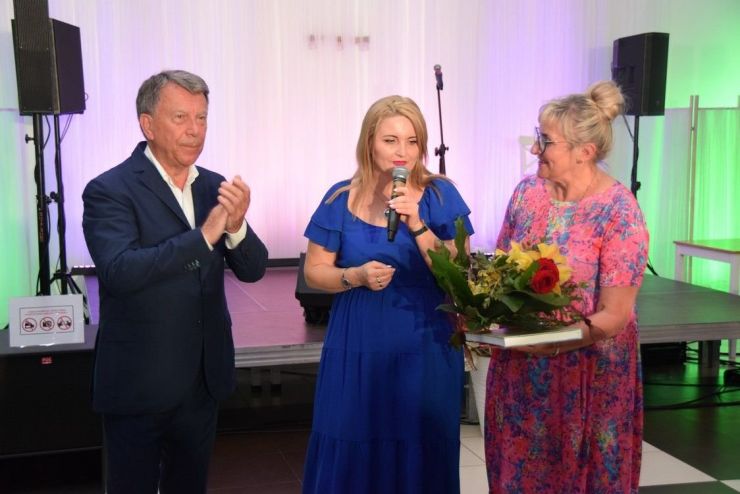 Wojciech Gąsowsski stoi z dwoma kobietami, jedna z nich trzyma kwiaty i książki.