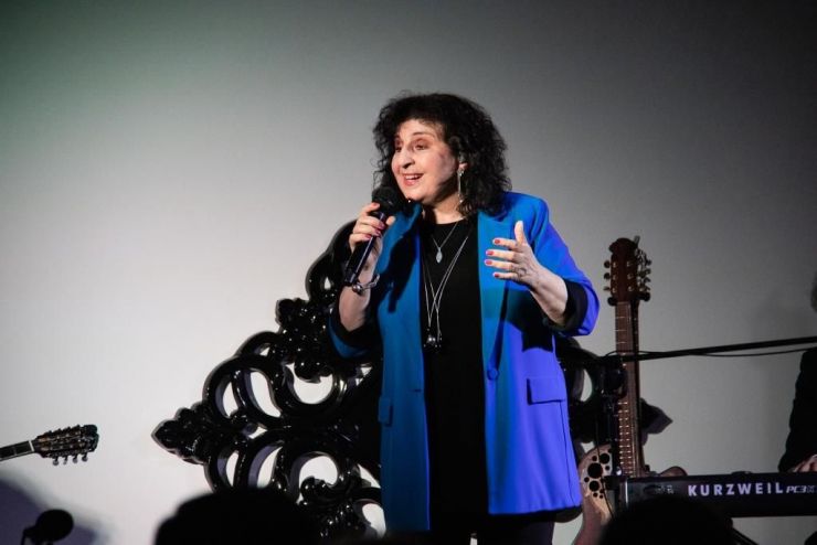 wokalistka ubrana na niebiesko stoi na scenie z mikrofonem.