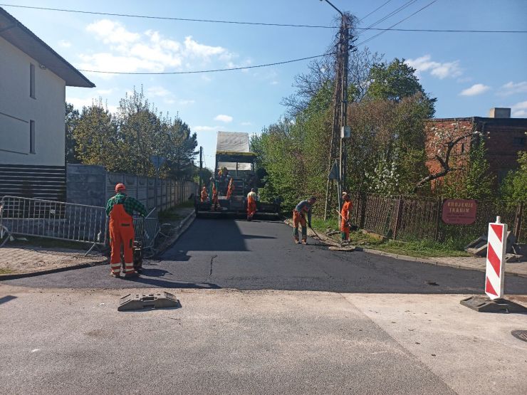 Pracownicy podczas wykonywania prac drogowych - kładą pierwszą warstwę asfaltową.
