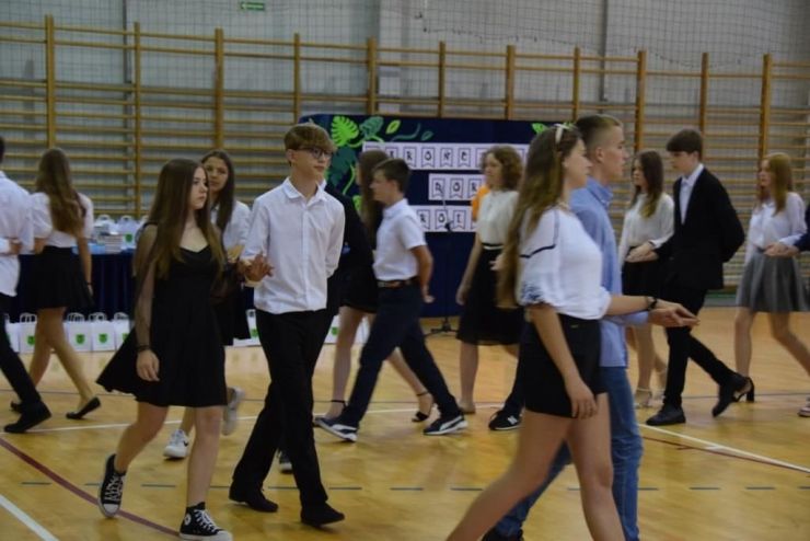 Uczniowie w parach trzymają się za ręce i tańczą poloneza