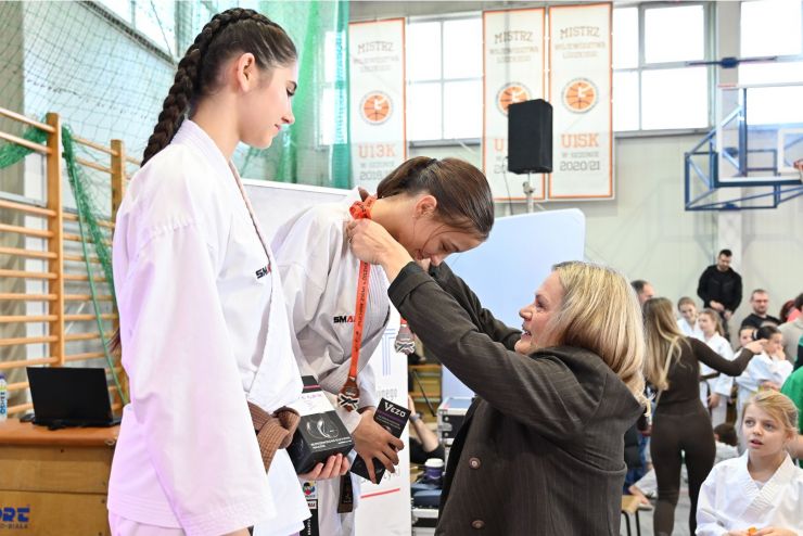 Kobieta zawiesza medal na szyi zawodniczki 