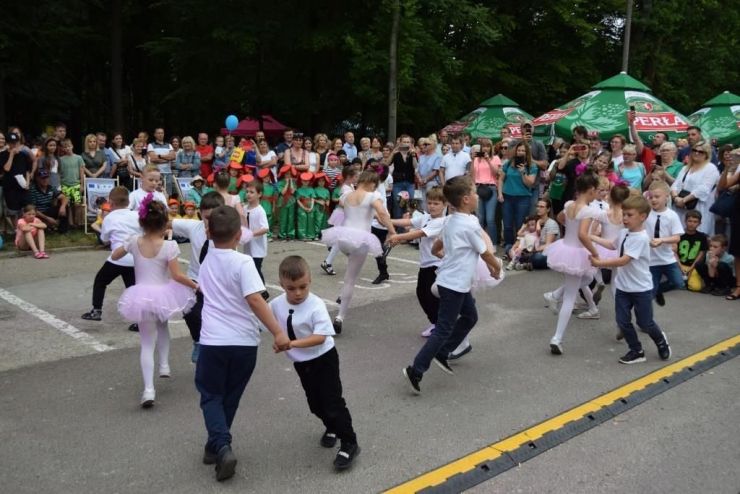 Grupa chłopców i dziewcząt tańczy w parach na placu przed sceną