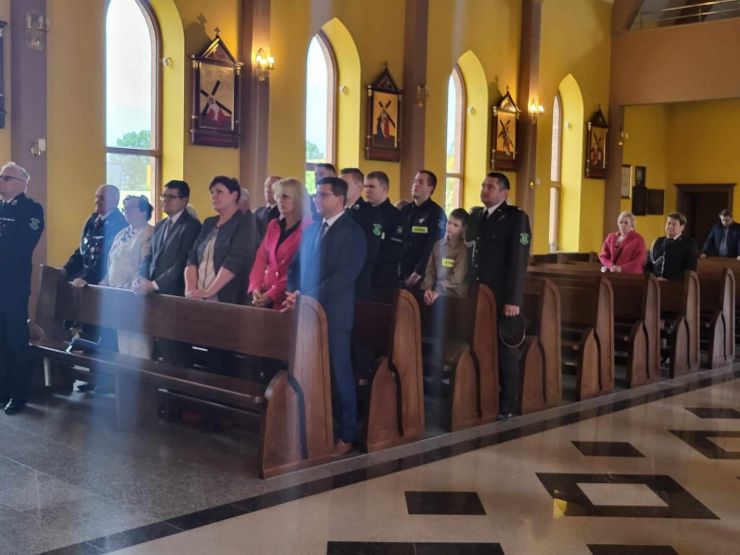 Uczestnicy mszy stoją w ławkach kościelnch