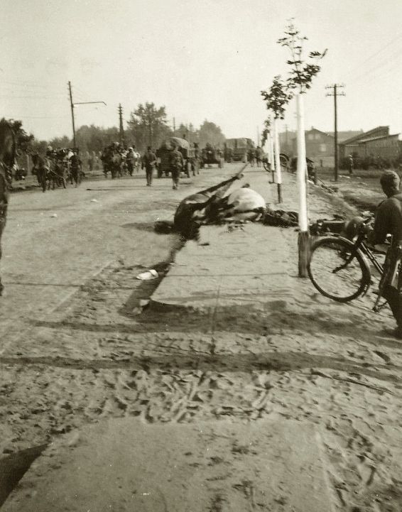 Czarno-białe zdjęcie ulicy z widocznymi pozostałościami po walkach