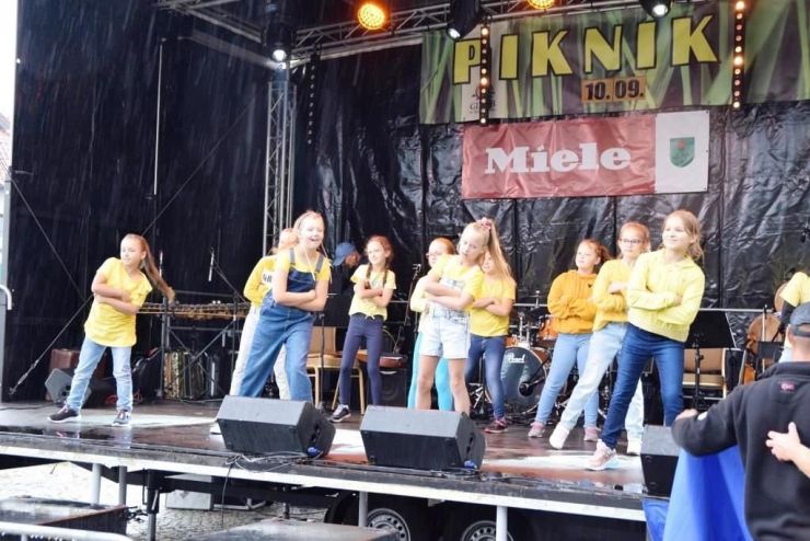 Na scenie młodzież szkolna podczas występu. Uczniowie ubrani w żółte koszulki i jeansy