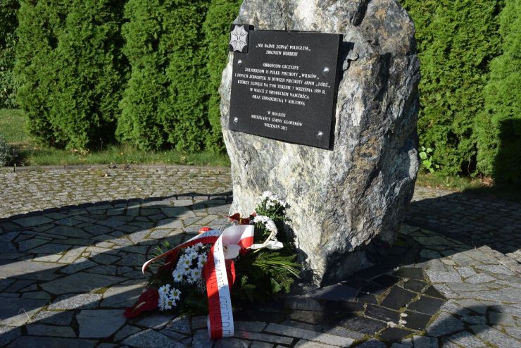 Obelisk i złożone pod nim kwiaty.