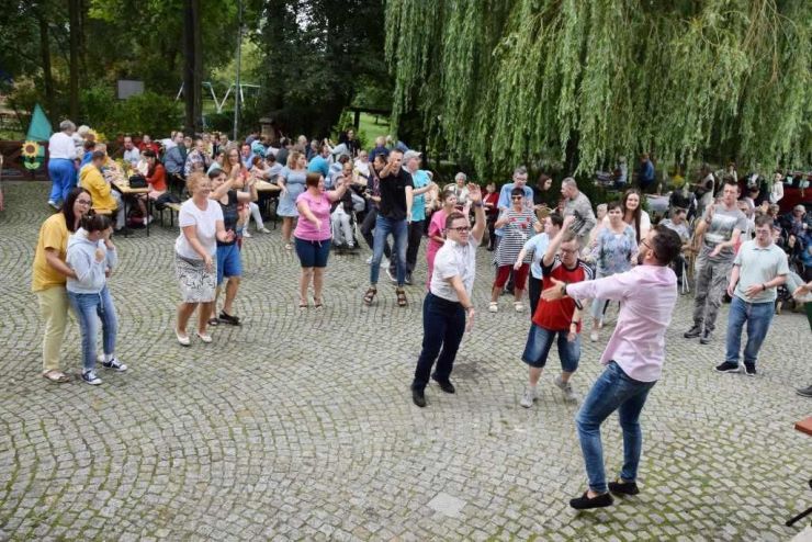 Grupa uczestników tańczy na terenie placu przy Domu Kultury