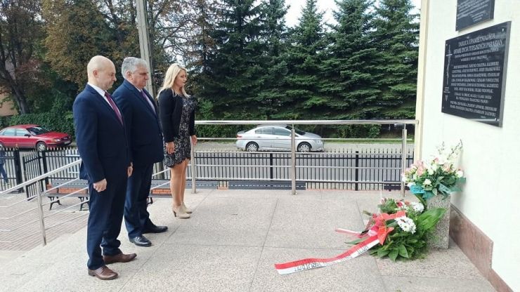 Wójt Adam Topolski, Sekretarz Monika Sroczyńska i Przewodniczący Rady Arkadiusz Jędrzejczyk składają kwiaty