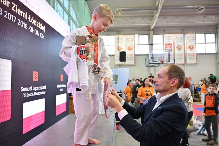 Mężczyzna wręcza dyplom zawodnikowi.