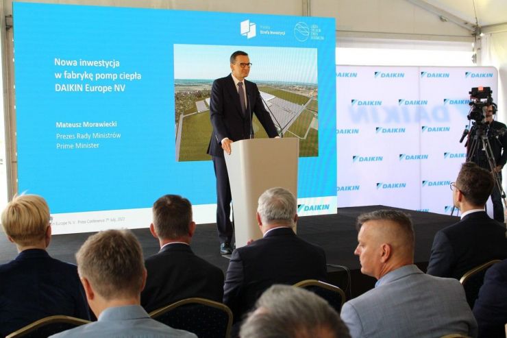 Premier Mateusz Morawiecki stoi przy mównicy na tle niebieska tablica z napisem Nowa inwestycja w fabrykę pomp ciepła DAIKIN Europe NV