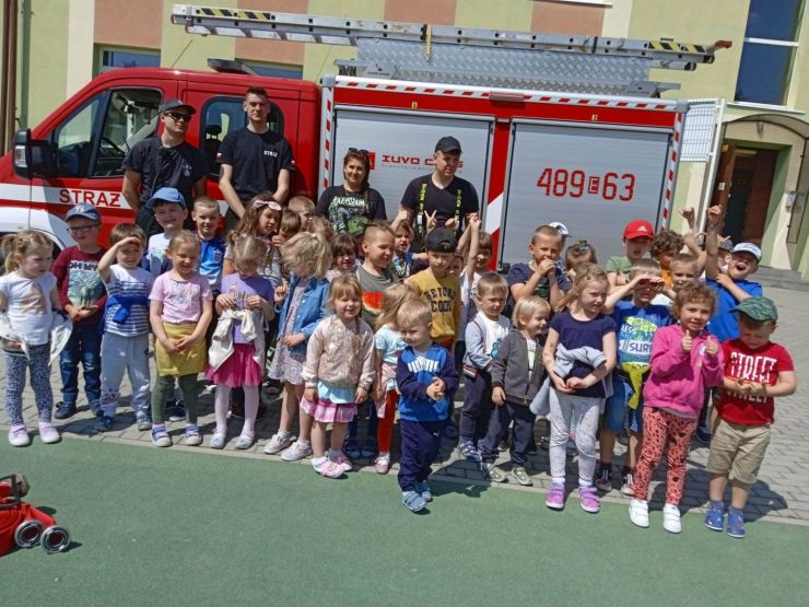 Na zdjęciu grupa dzieci stoi przed samochodem strażackim