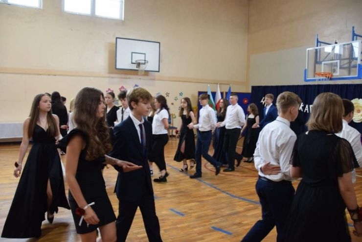 Uczniowie w parach tańczą poloneza na sali