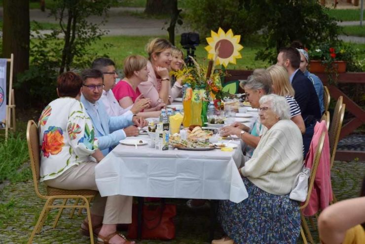 Przy udekorowanym stole siedzą uczestnicy wydarzenia - przedstawiciele władz lokalnych.