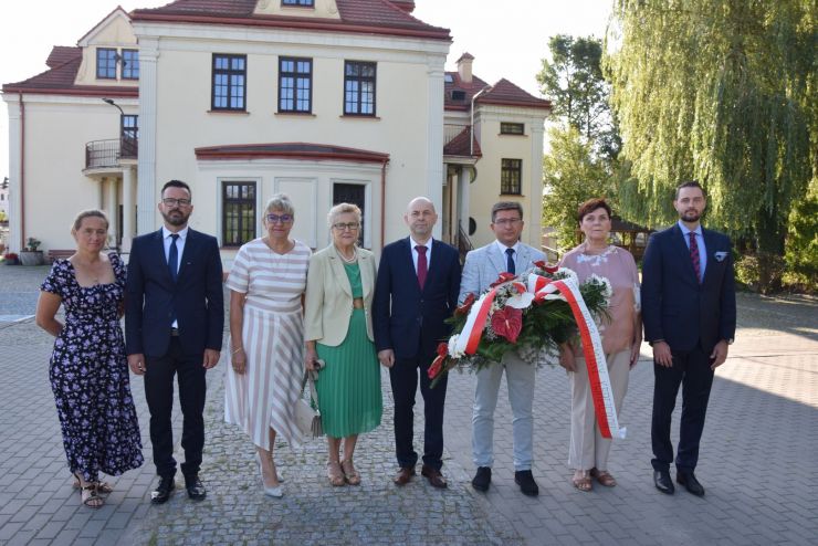 Stoi osiem osób - jedna trzyma kwiaty. 