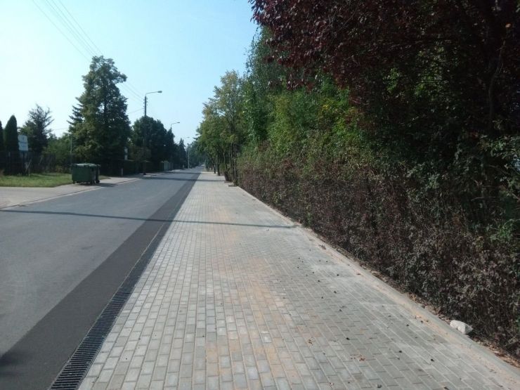 Chodnik z kostki betonowej, po lewej widoczny fragment ulicy.