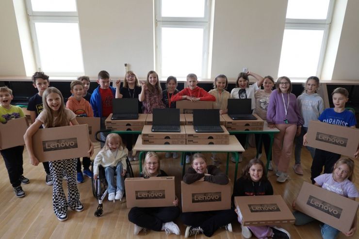 Grupa dzieci trzymająca w dłoniach kartony z laptopami.