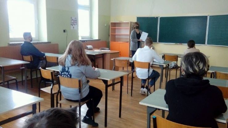 pięcioro uczniów siedzących w ławkach przed nimi nauczycielka