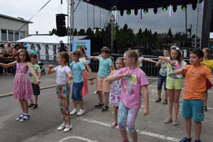 Grupa dzieci ubranych na kolorowo tańczy przed sceną