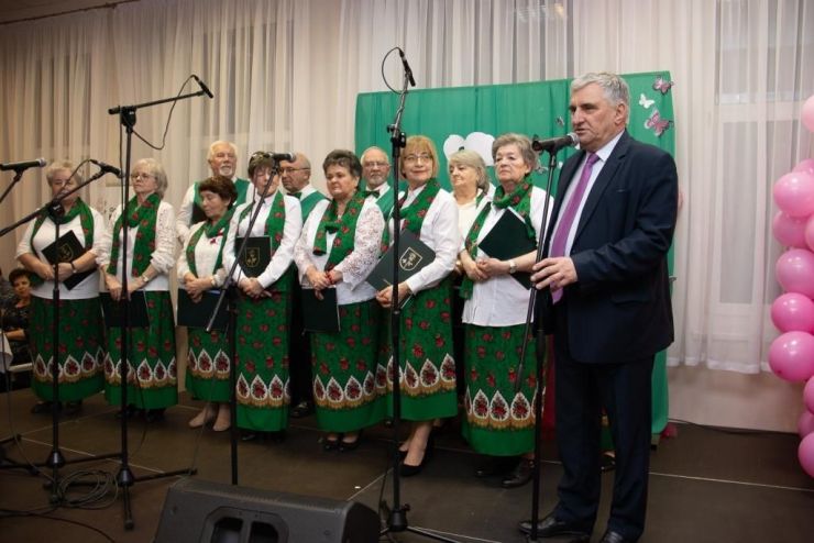 Kobiety w biało zielonych strojach stoją na scenie z mikrofonami