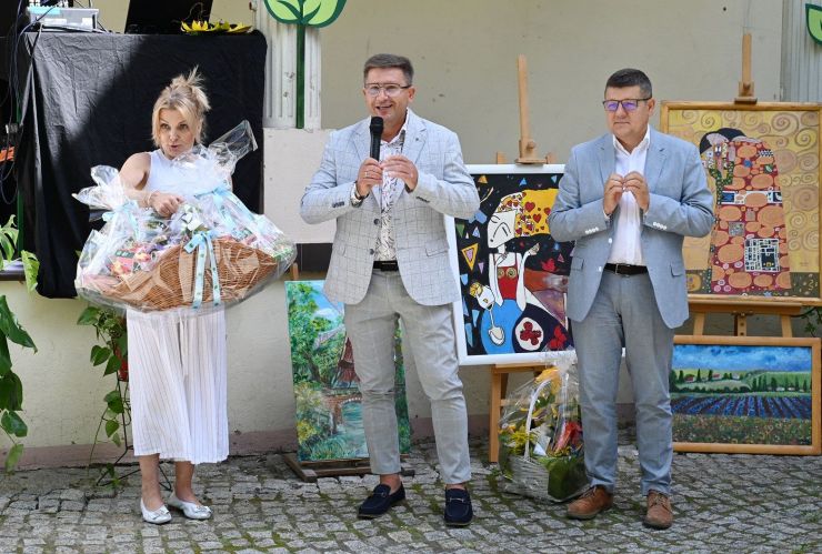 Kobieta oraz dwóch mężczyzn przemawiają do zebranych.