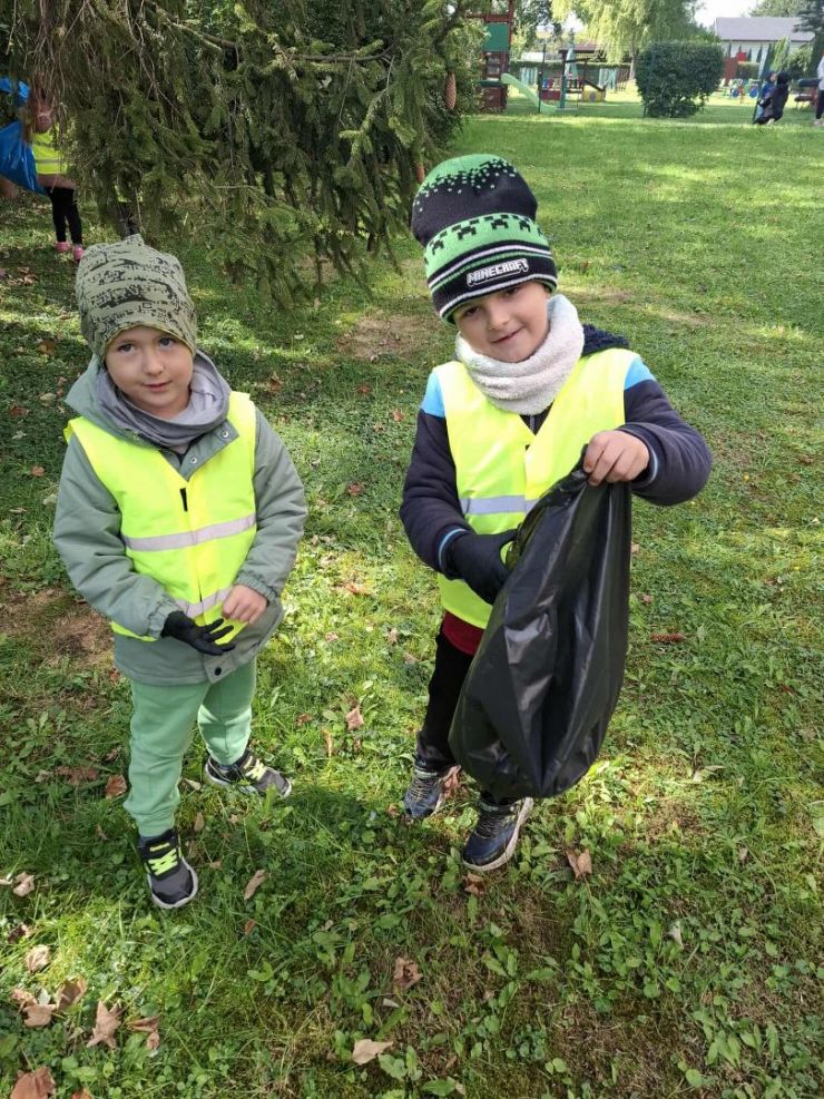 dwoje dzieci jedno trzyma w dłoniach worek na śmieci